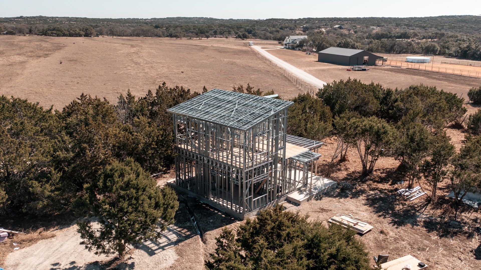Aerial view of a cold-formed steel home frame on Texas Hill Country acreage with open pasture and cedar trees
